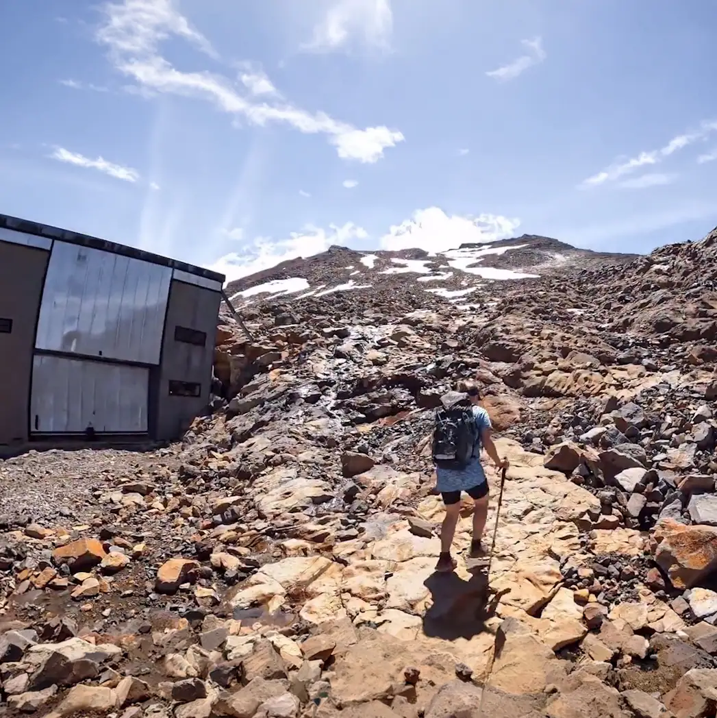 Hiker starting from the Turoa Skifield up towards the highest peak of Ruapehu, Tahurangi, on the distant skyline