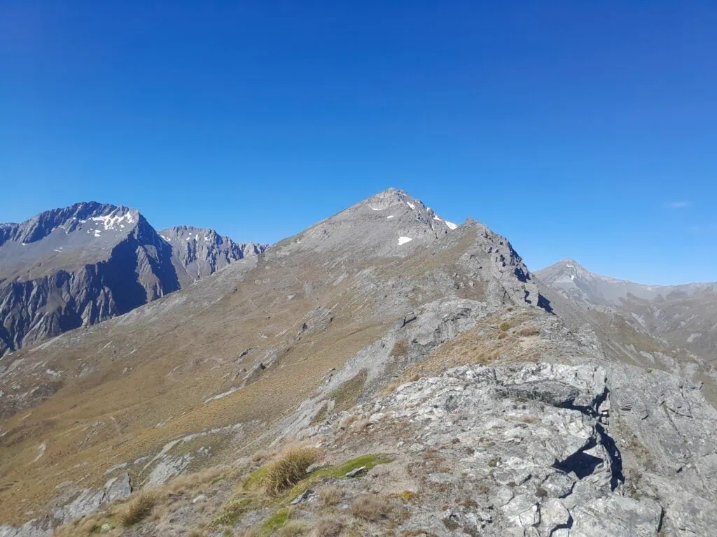 View looking toward Black Peak from the McIntosh Peak ridgeline, Southern Alps, New Zealand. High-altitude rocky terrain and scree slopes under a clear blue sky