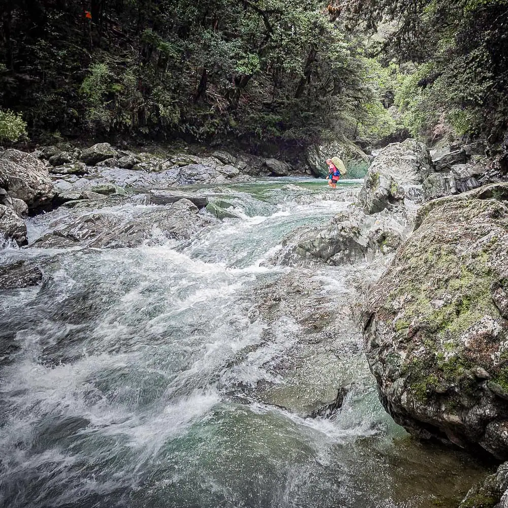 Hiker crosses a fast flowing Goulter River