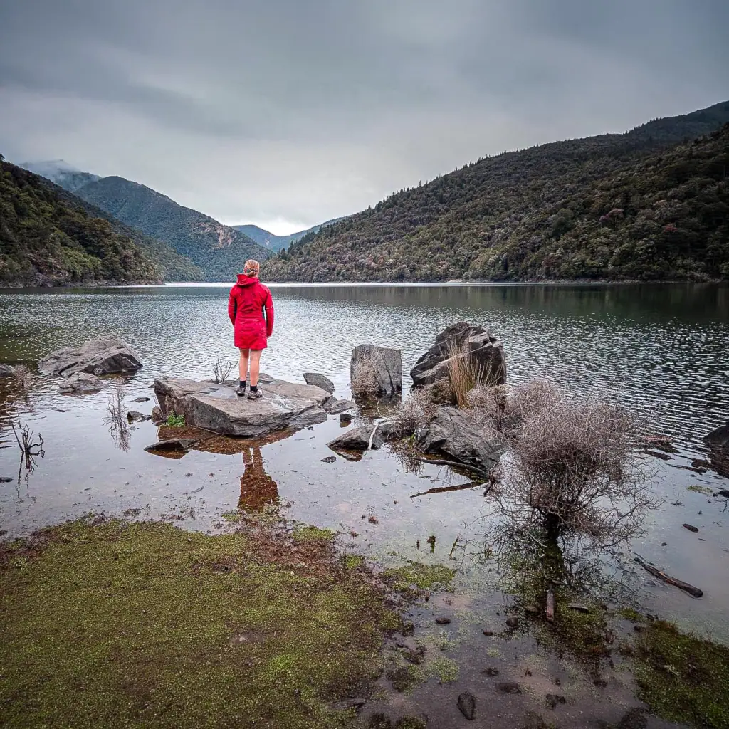 Hiker looking over a calm Lake Chalice on a cloudy day