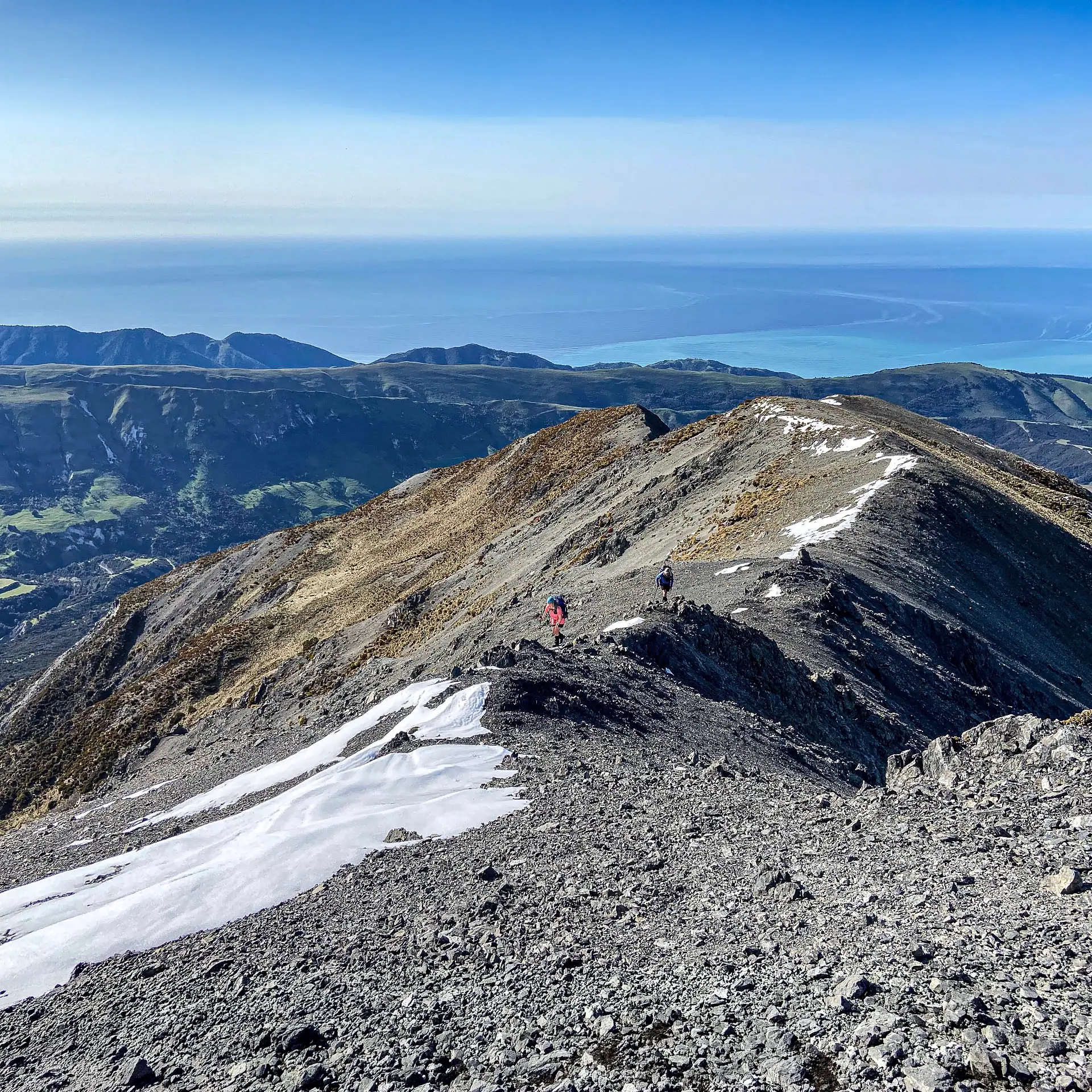 Two hikers low on the ridge above Jordan Stream leading to the summit of Te Ao Whekere