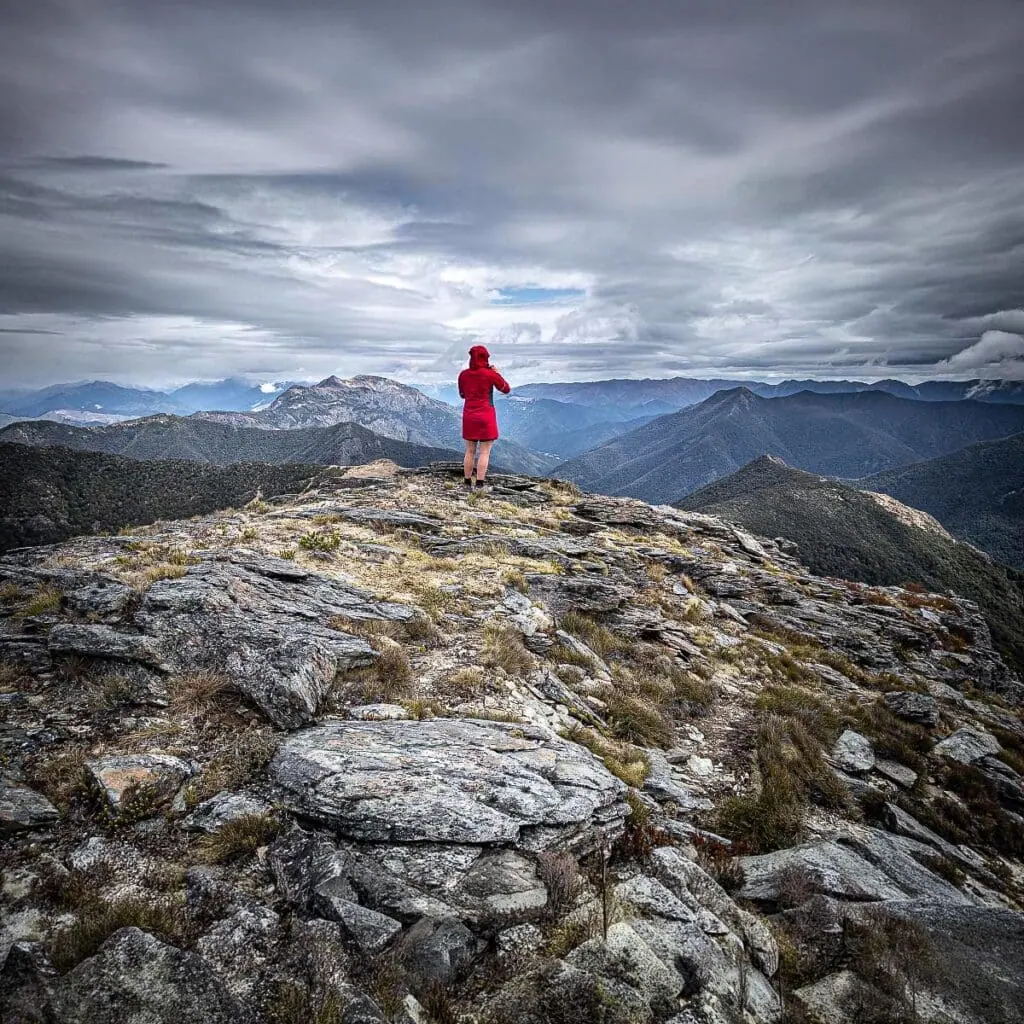 Hiker on the summit of Point 1522 with a clear view to the southern Richmond Range peaks