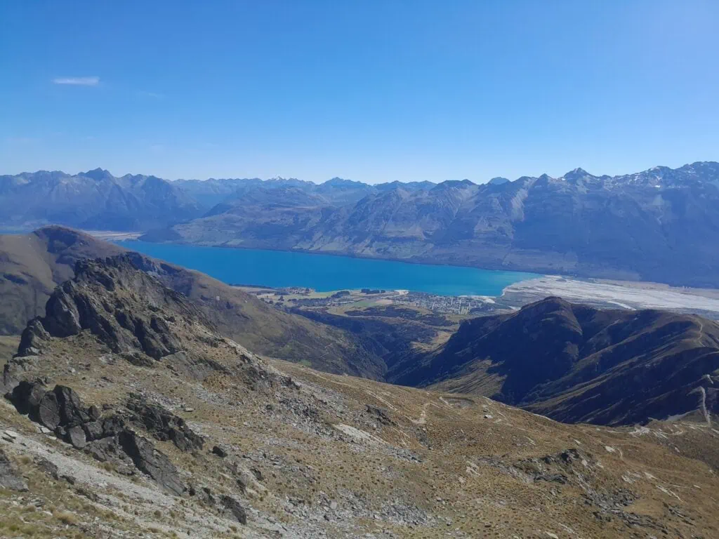 High-altitude view looking down from the above McIntosh hut towards the McIntosh Loop Track, Lake Wakatipu and Glenorchy, showcasing the rugged alpine terrain of the Whakaari Conservation Area, New Zealand