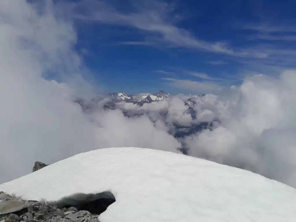 Swirling cloud with a view of snowcapped mountains in the Adams Wilderness area including the Garden of Eden from the summit of Mt Adams
