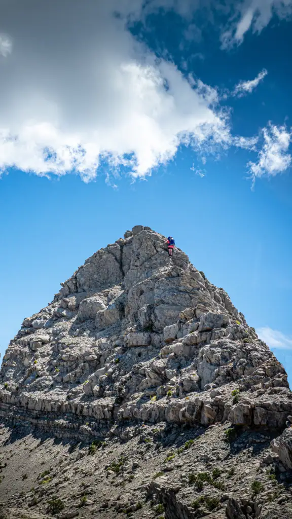 A hike high up a steep and high mudstone formation wearing a large blue pack in the Matiri Range at the Haystack