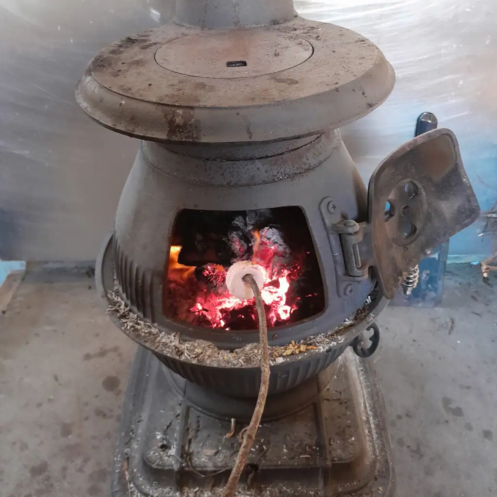 Toasting marshmallows on a stick in a woodburner in Jam Hut in Seaward Kaikōura Range, Ka Whata Tu o Rakihouia Clarence