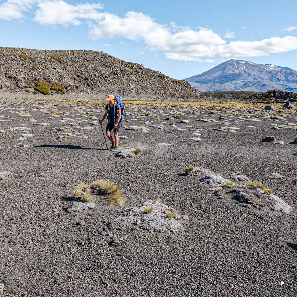 Hiker on the sandy Rangipo Desert carrying a backpack and with a fine sunny day and Mt Ruapehu in the background