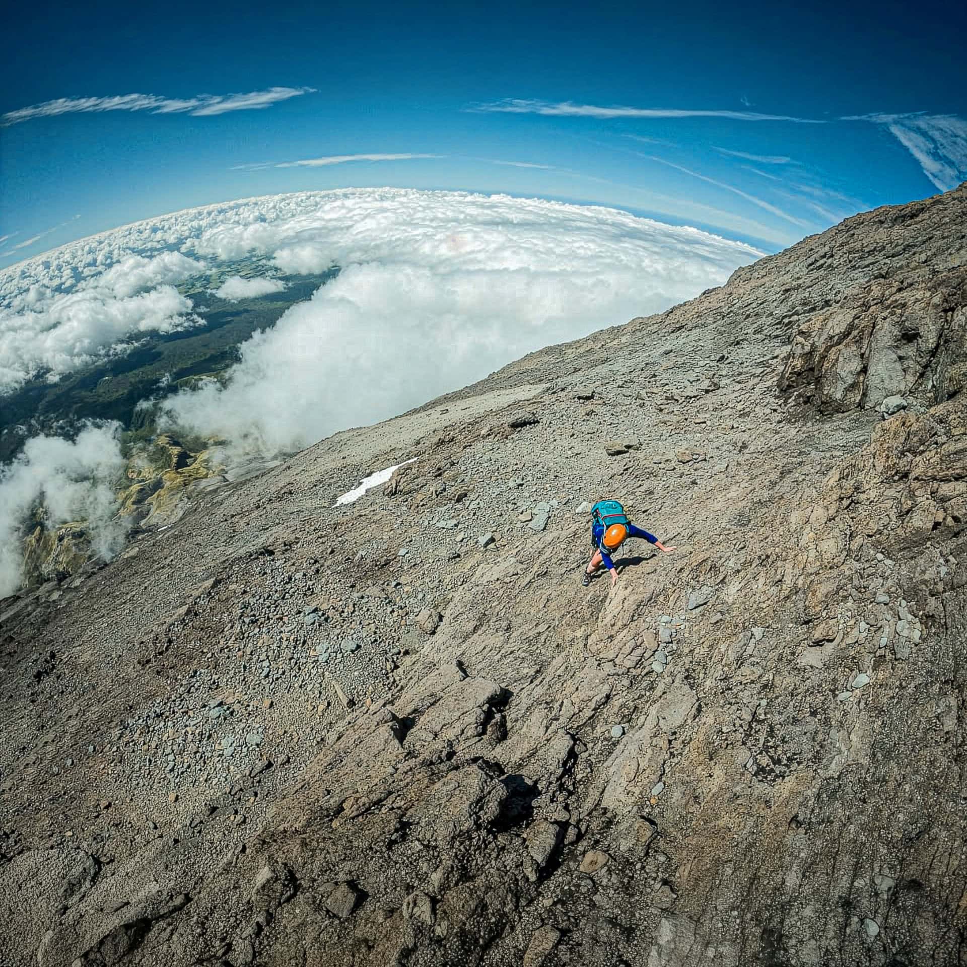 A climber makes their way up the East Ridge on Mt Taraniki high above the clouds and the Manganui ski field on a unusually calm and clear mountain day.