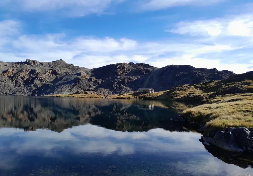 A landscape photo of reflection of Angelus hut in Lake Angelus in Nelson Lakes National Park