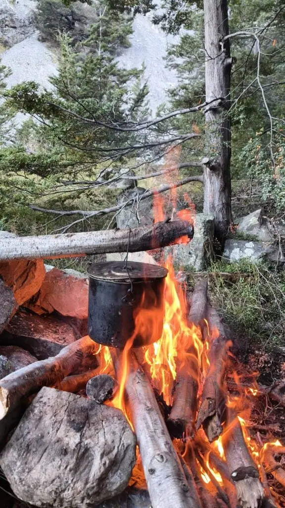 A close up photo of a campfire with a pot with water on a river terrace on the Bush Stream track in the Two Thumb Range