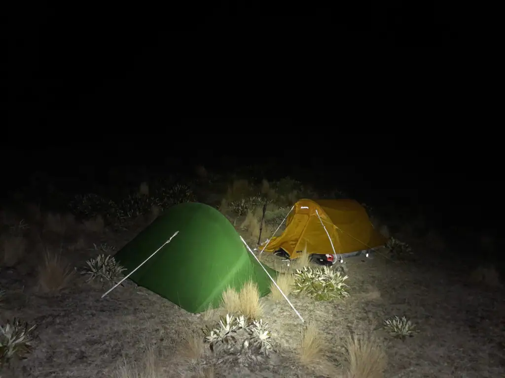 a green and yellow tent pitched in the dark on George Spur on the route to Mt Tarahaka in Ka Whata Tu o Rakihouia Conservation Park