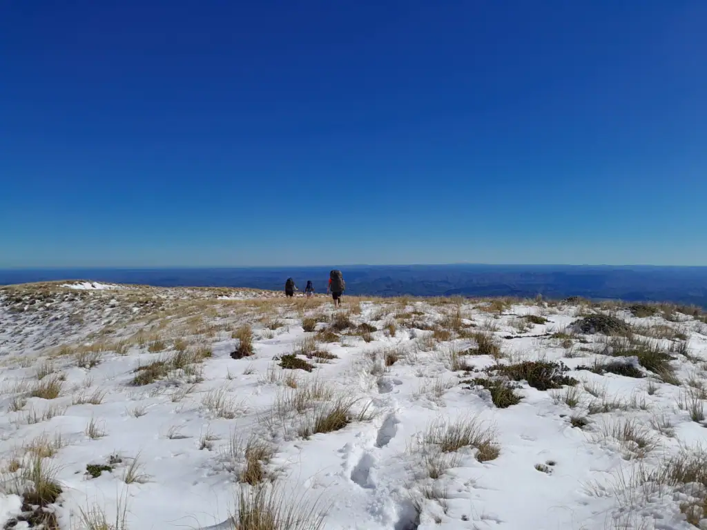 Distant view of snow-capped Mt Taranaki on the horizon, framed by snow covered ridgelines of the Ruahine Range.
