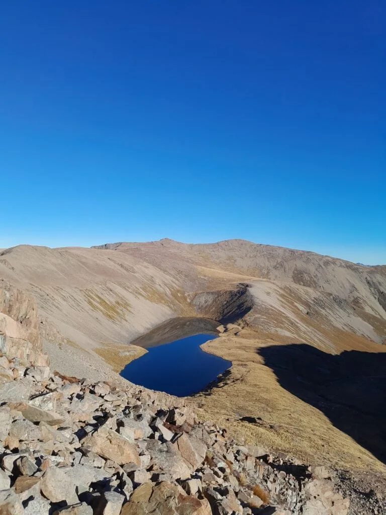 Above Dumb-bell Lake with its partially frozen surface above Lake Ohau. Climbing towards Mt Sutton with Pinnacle in the background