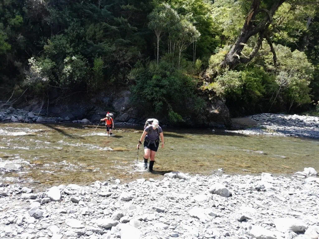 Two trampers cross a shallow river to get to Iron Bark hut int he Ruahine Range
