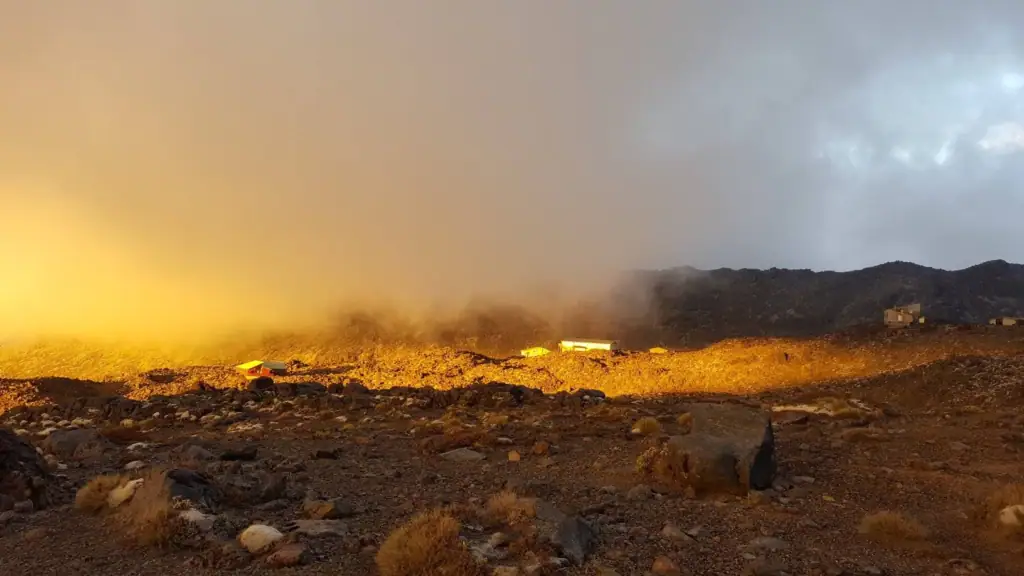 The golden light from the setting sun amongst cloud in Iwikau Village at the top of the Bruce Road with club lodges in Tongariro National Park