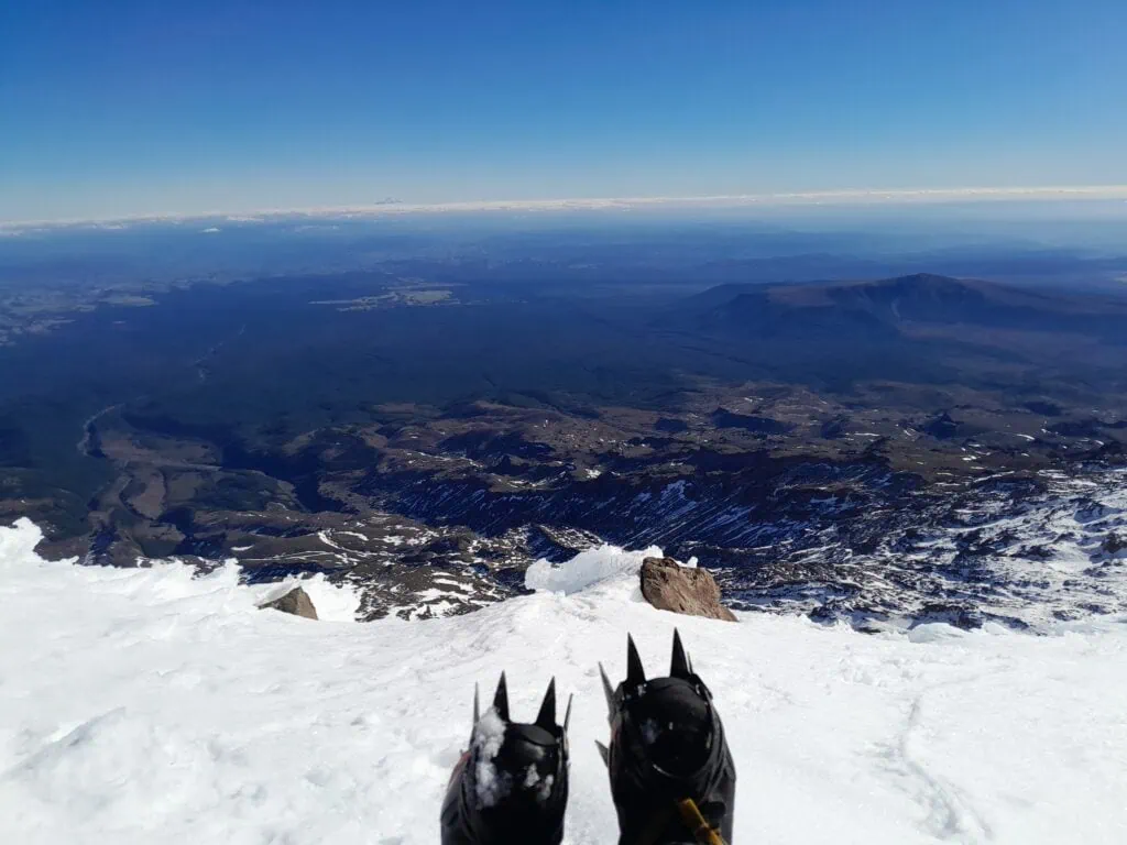 A pair of crampons on a snowy slope on Te Ātaahua, Mt Ruapehu in  Tongariro National Park with Mt Taranaki on the horizon