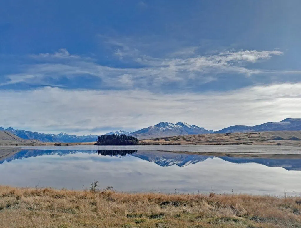 Perfect mountain reflection on the glassy surface of Lake Clearwater with tussock flats in Hakatere Conservation Park, Canterbury