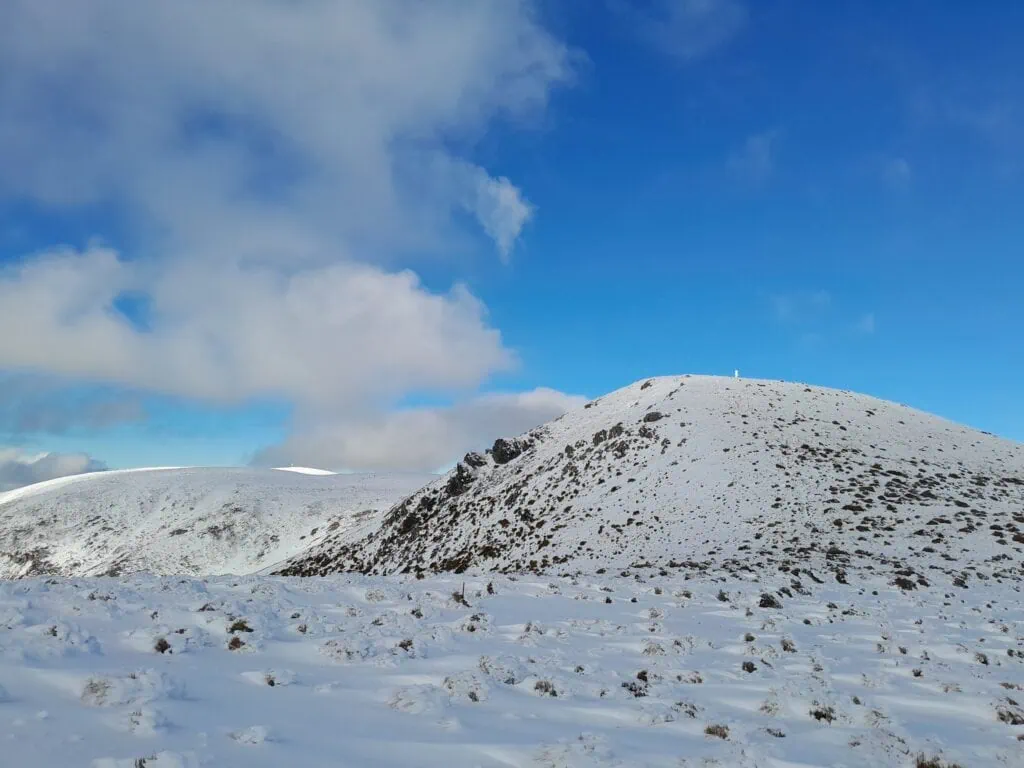 Looking back across a snow-covered alpine ridge line toward the rounded summit of Mt Oxford in winter., Mt Oxford Forest, Canterbury