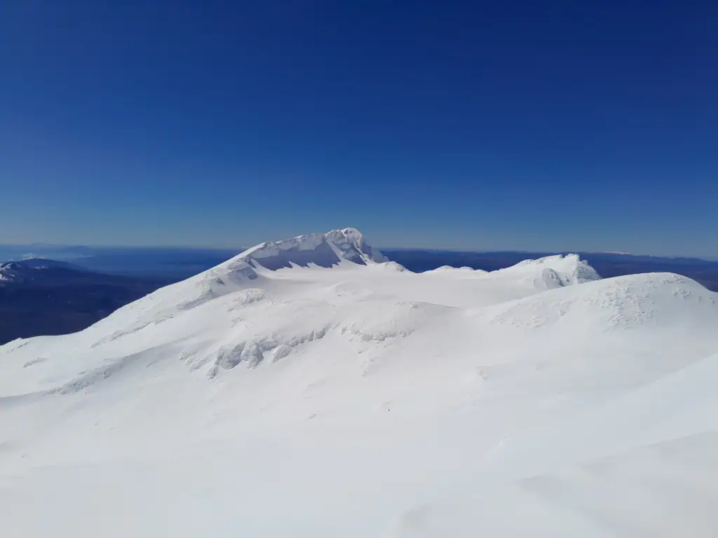Looking across the wide, snow-filled Summit Plateau toward Te Heuheu peak and Tukino Peak on the eastern side of the Mt Ruapehu crater rim.