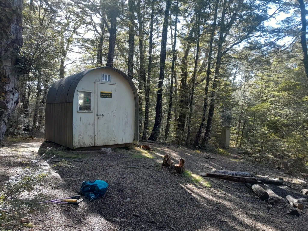 The Basic 2-bunk Bob’s Camp Bivouac, a white metal curved bivvy, nestled within the beech forest just off Bob's Camp Route in Mount Thomas Forest Conservation Area, Canterbury Foothills.