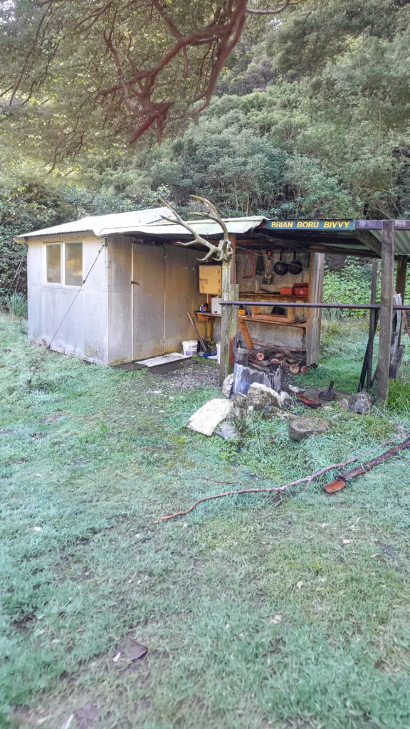 The rustic corrugated-iron Brian Boru Bivvy hut with mounted deer antlers, surrounded by frost-covered grass. Located in Isolated Hill Reserve in the Seaward Kaikōura Range