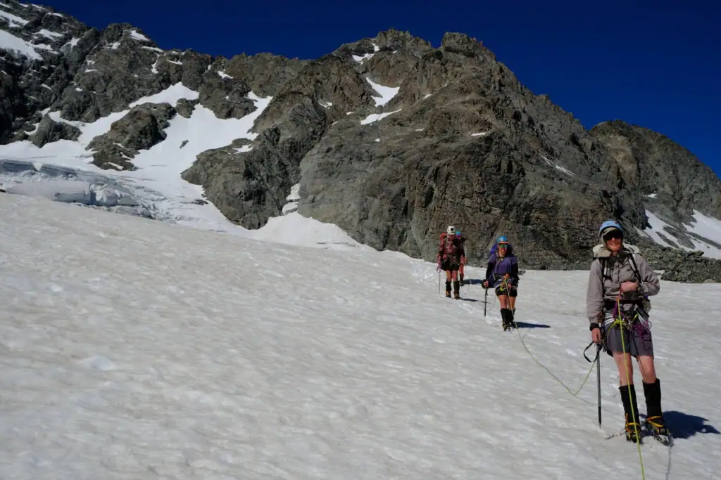 Roped mountaineers navigating a vast, sun-drenched slope on the Ashburton Glacier during a challenging alpine crossing, Hakatere Conservation Park, Canterbury