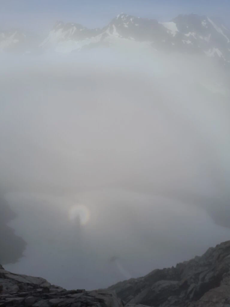 A rare Brocken spectre optical phenomenon showing a shadow cast upon misty clouds surrounded by a faint rainbow halo on Mt Ollivier, Aoraki/Mt Cook National Park