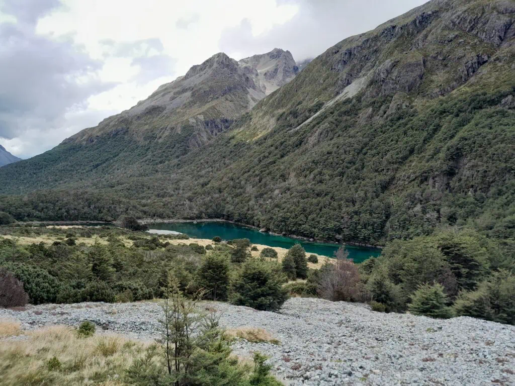 Elevated view looking down at Lake Rotomairewhenua / Blue Lake nestled in a mountain valley. on the Waiau Pass Route, Nelson lakes National Park. 
