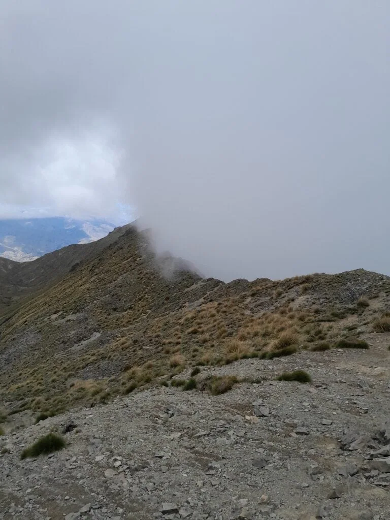 Thick mountain cloud rolling over a sharp alpine ridge on the approach to Altimarloch from Mt Harkness. in Ferny Gair Conservation Area, Marlborough