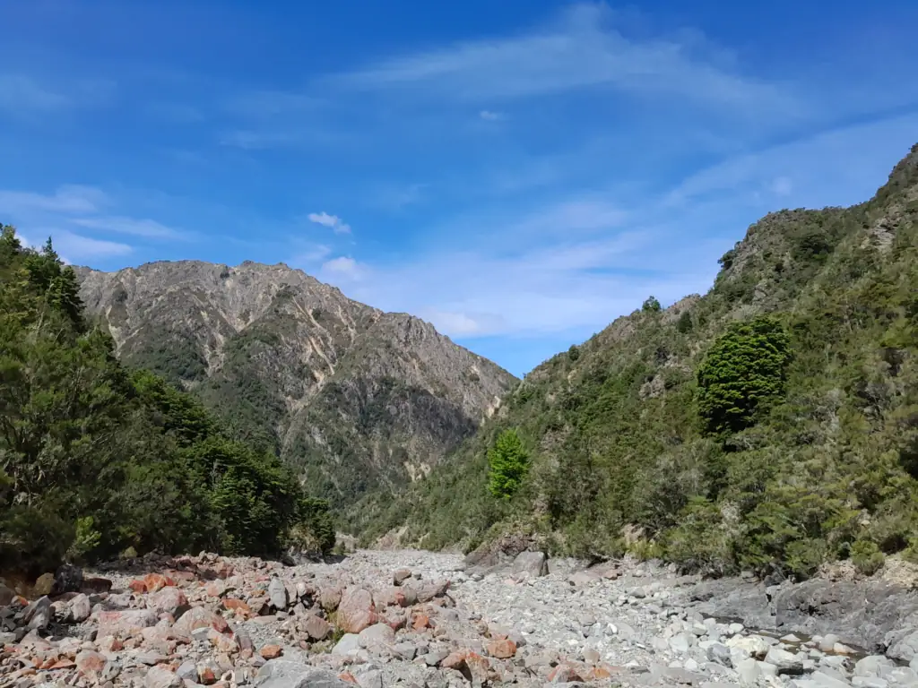 Rocky, dry bed of Gosling Stream surrounded by green native bush and steep mountain slopes in the Raglan Range, Marlborough.