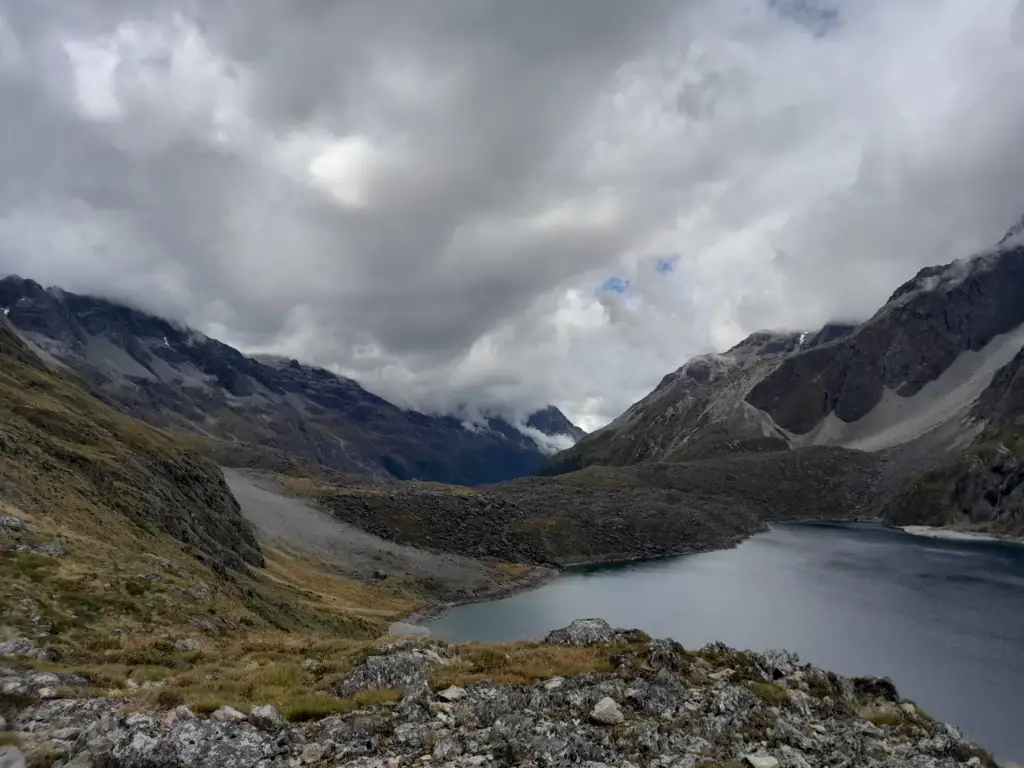 Large terminal moraine wall damming Lake Constance / Rotopōhueroa under a dramatic, cloudy alpine sky near Waiau Pass, Nelson Lakes National Park