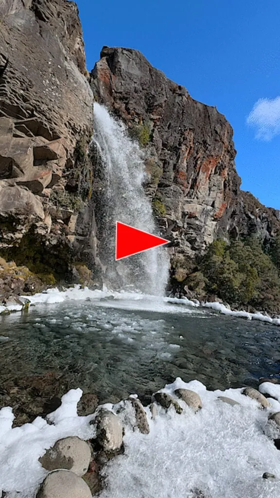 Taranaki Falls in winter with ice encrusted rocks and ice floating in the poo;