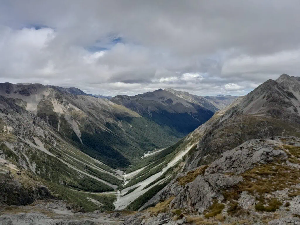 Vast U-shaped Waiau Uwha River valley stretching out below steep alpine scree slopes from the summit of Waiau Pass in Nelson Lakes & St James Conservation Area.